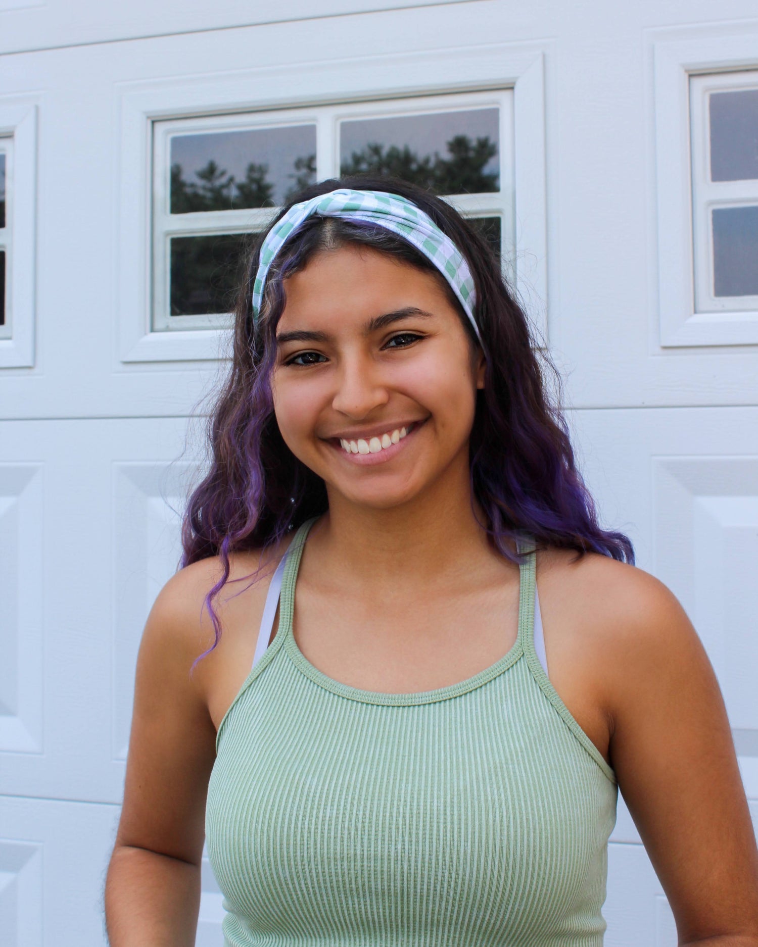 A girl with purple hair wearing a green gingham headband and green tank top