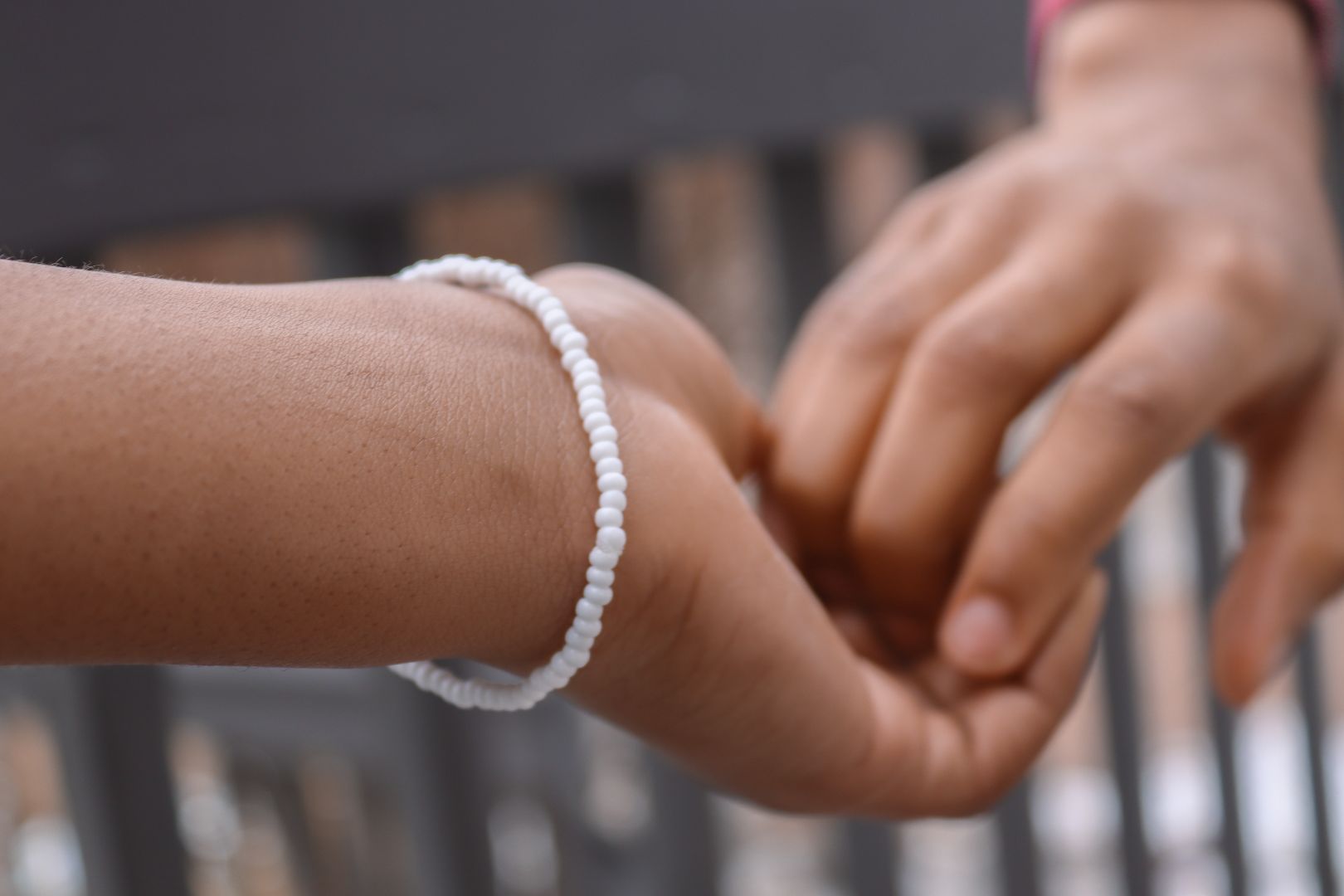 One hand in another, one wrist is wearing a white beaded bracelet